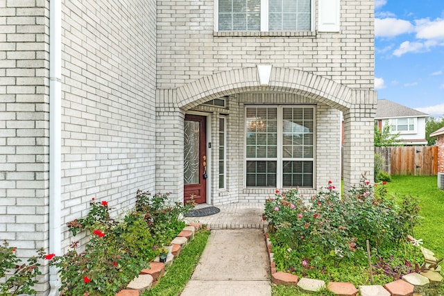property entrance with brick siding and fence