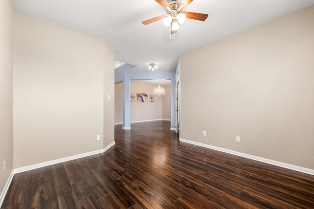 spare room featuring a chandelier, dark wood finished floors, ceiling fan, and baseboards