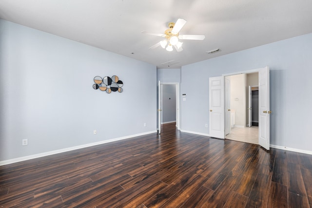 spare room with dark wood-type flooring, a ceiling fan, and baseboards