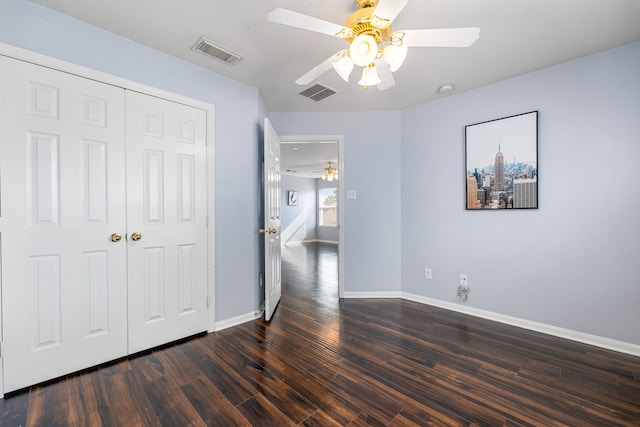 unfurnished bedroom featuring dark wood-type flooring, baseboards, a closet, and a ceiling fan