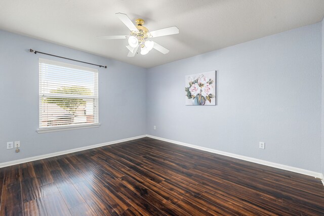 unfurnished room featuring baseboards, a ceiling fan, and dark wood finished floors