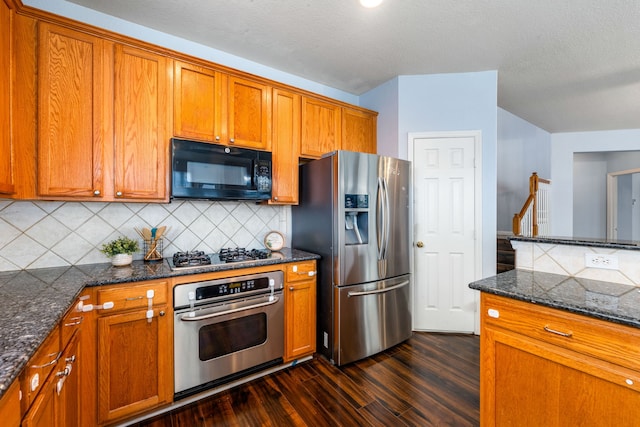 kitchen featuring appliances with stainless steel finishes, dark wood finished floors, brown cabinetry, and backsplash