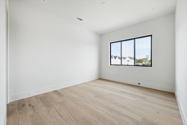 unfurnished room with baseboards, light wood-style floors, and visible vents