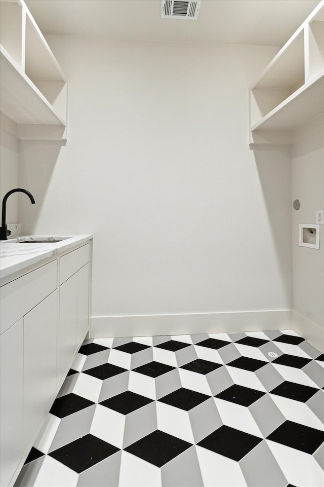 washroom with a sink, cabinet space, visible vents, tile patterned floors, and hookup for a washing machine