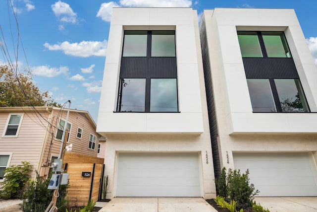 view of front of home with concrete driveway, an attached garage, and stucco siding