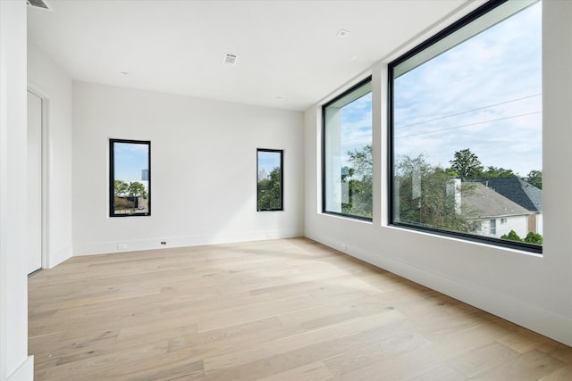 unfurnished room with baseboards, light wood-style floors, and a healthy amount of sunlight
