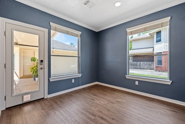 unfurnished room with plenty of natural light, wood finished floors, ornamental molding, and baseboards