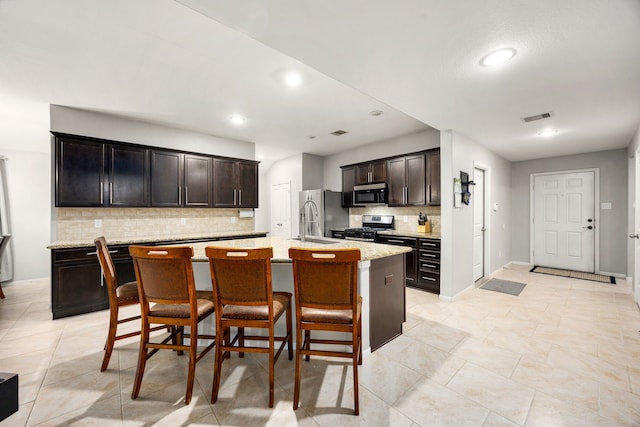 29014 Jacobs River Dr, Katy, TX 77494 - kitchen with appliances with stainless steel finishes, a sink, backsplash, an island with sink, and a kitchen breakfast bar