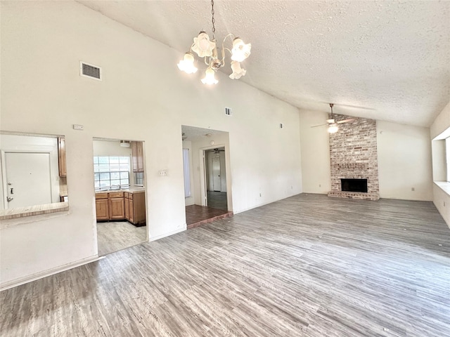 4230 E Terrace Creek Cir, Houston, TX 77014 - unfurnished living room with light wood-style flooring, a textured ceiling, visible vents, ceiling fan with notable chandelier, and a brick fireplace