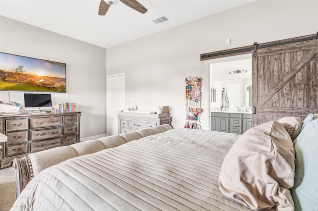bedroom featuring a ceiling fan, a barn door, ensuite bath, and visible vents