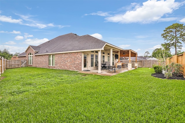 rear view of property with a yard, a patio area, brick siding, and a fenced backyard