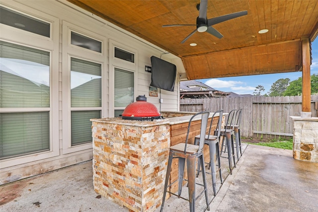 view of patio with outdoor dry bar, fence, and ceiling fan