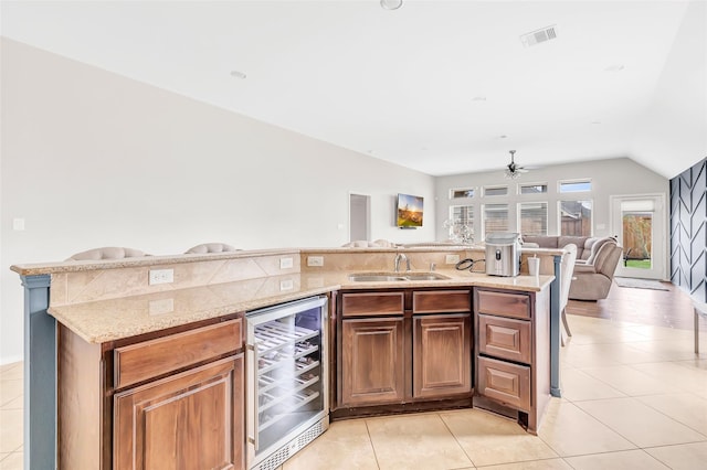 kitchen featuring wine cooler, open floor plan, light tile patterned floors, and a sink