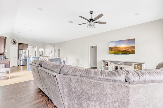 living area with ceiling fan, arched walkways, visible vents, and wood finished floors