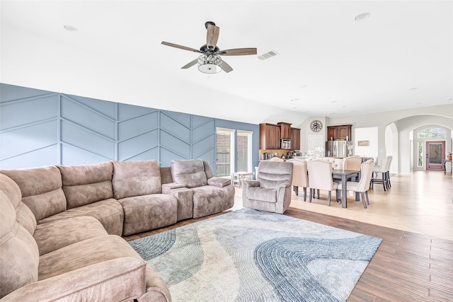 living area featuring recessed lighting, visible vents, ceiling fan, arched walkways, and light wood-style floors