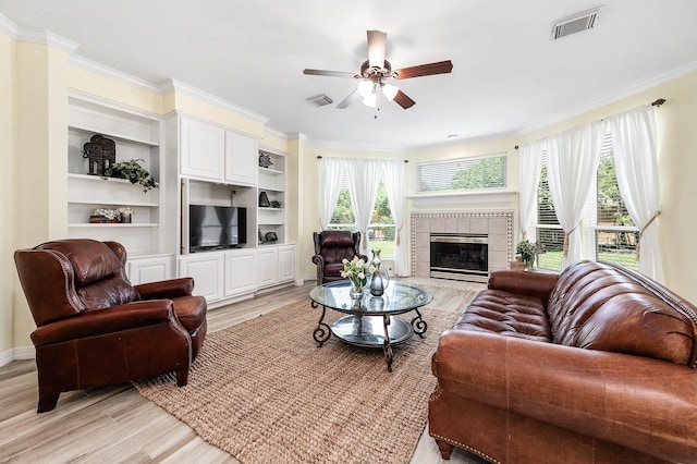 1910 Stormcroft Cir, Katy, TX 77450 - living area with ornamental molding, a ceiling fan, light wood-style flooring, a tile fireplace, and baseboards