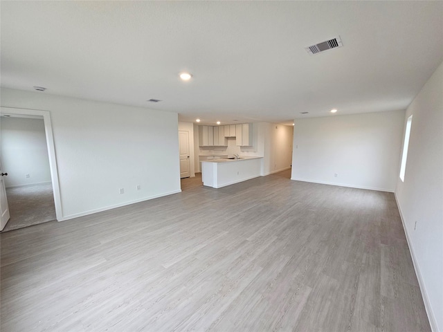 unfurnished living room with baseboards, recessed lighting, light wood-style flooring, and visible vents