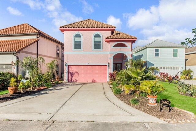 mediterranean / spanish-style home with concrete driveway, a garage, stucco siding, a tiled roof, and a front lawn