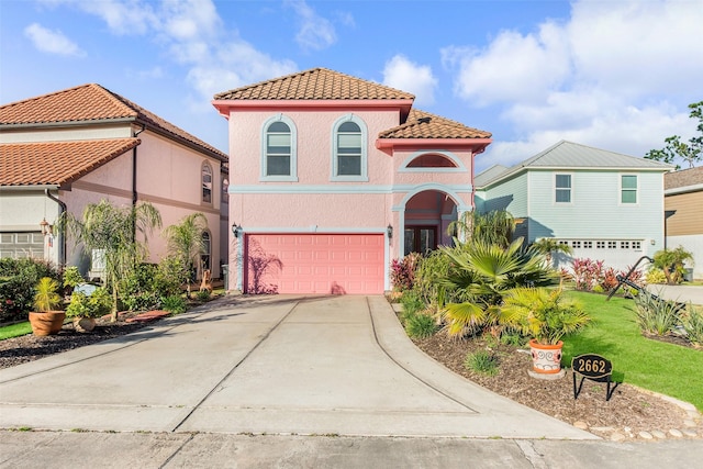 2662 E Bayshore Dr, Dickinson, TX 77539 - mediterranean / spanish house featuring an attached garage, a tiled roof, concrete driveway, stucco siding, and a front lawn