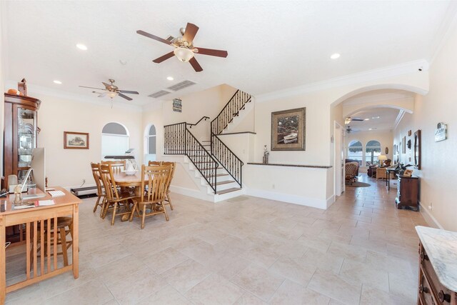 dining room featuring ceiling fan, ornamental molding, arched walkways, and baseboards