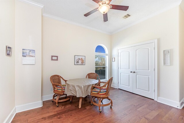 dining room featuring wood finished floors, a ceiling fan, crown molding, visible vents, and baseboards