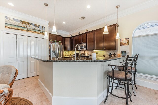 kitchen with visible vents, dark brown cabinetry, backsplash, stainless steel appliances, and dark stone counters