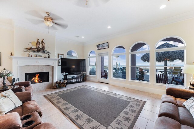 tiled living room featuring a fireplace, ornamental molding, a ceiling fan, and recessed lighting