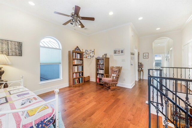 living area featuring arched walkways, an upstairs landing, light wood-type flooring, and plenty of natural light