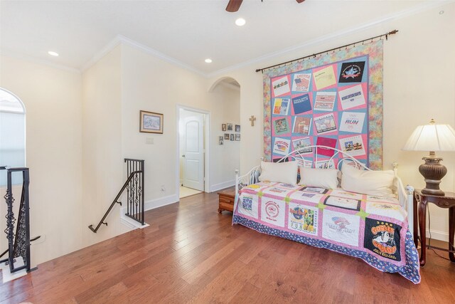 bedroom with crown molding, recessed lighting, arched walkways, and wood finished floors