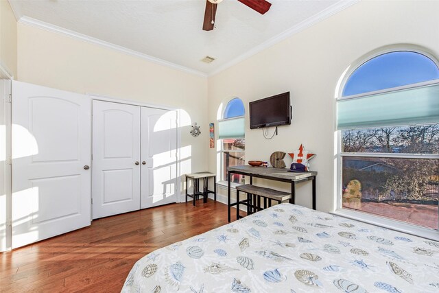 bedroom with wood finished floors, a closet, crown molding, visible vents, and ceiling fan