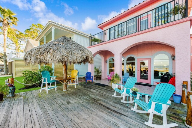 rear view of property with a wooden deck, stucco siding, and a balcony
