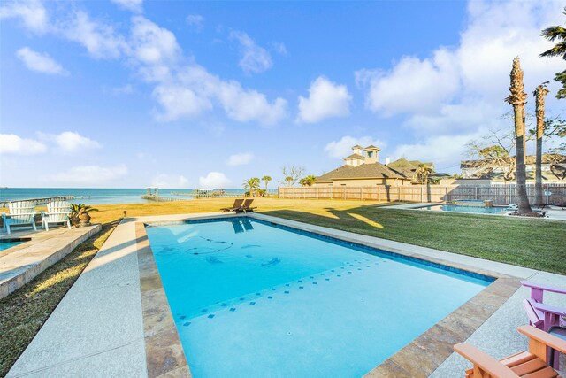 view of swimming pool featuring a water view, fence, a lawn, a patio area, and a fenced in pool