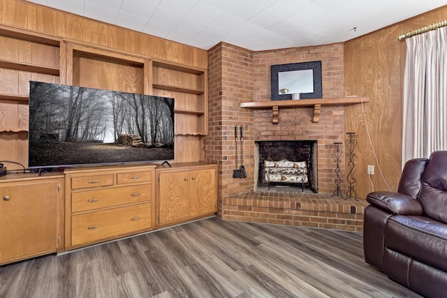 living room featuring wood finished floors, wooden walls, a fireplace, and built in shelves