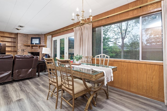 dining area with wooden walls, a fireplace, a chandelier, and wood finished floors