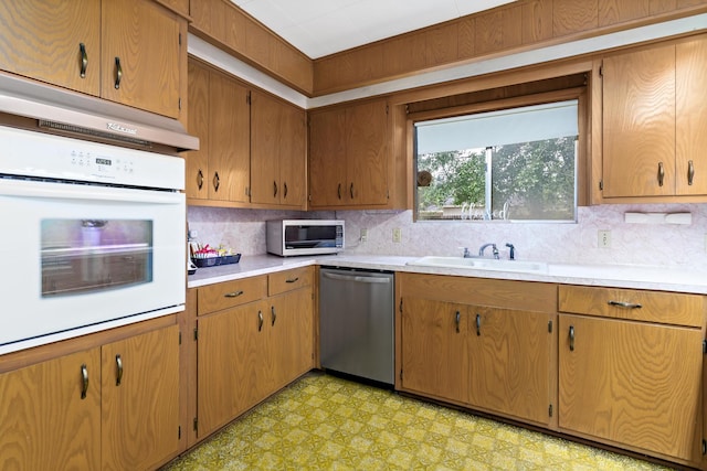 kitchen with a sink, light floors, decorative backsplash, and appliances with stainless steel finishes