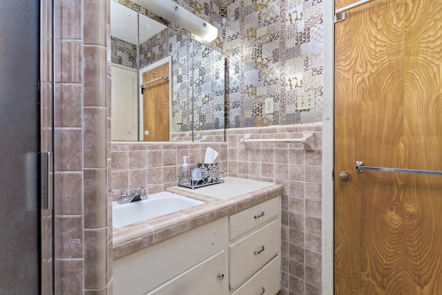 bathroom with vanity, tile walls, and wallpapered walls