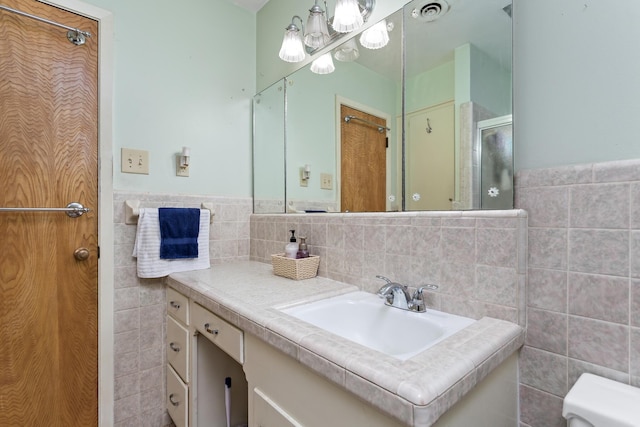 bathroom featuring toilet, a shower with shower door, tile walls, visible vents, and vanity
