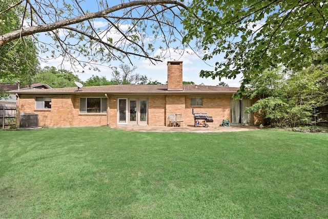 rear view of property featuring a yard, brick siding, fence, and a chimney