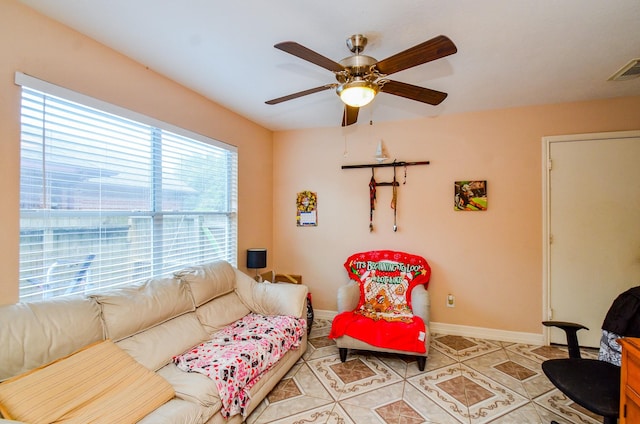 living room featuring ceiling fan, baseboards, and light tile patterned floors