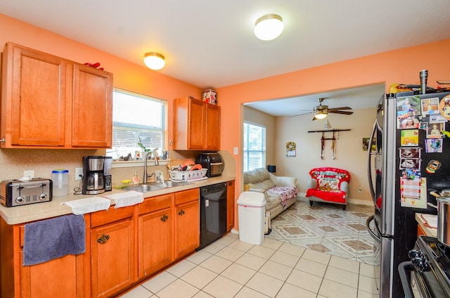 kitchen with a sink, black appliances, light countertops, open floor plan, and healthy amount of natural light