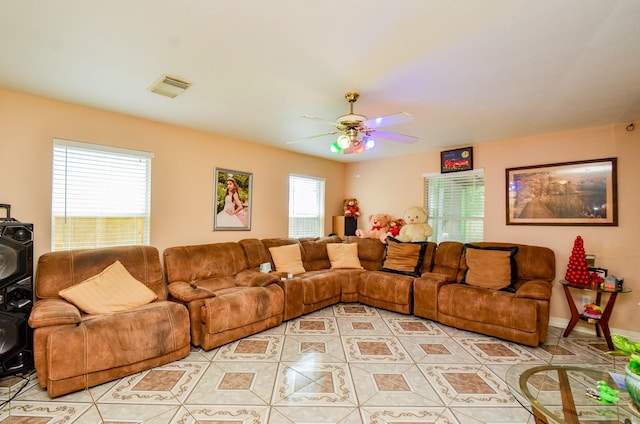 living area with light tile patterned floors, ceiling fan, plenty of natural light, and baseboards