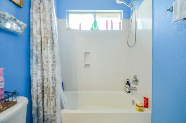 bathroom with shower / bathtub combination with curtain and toilet