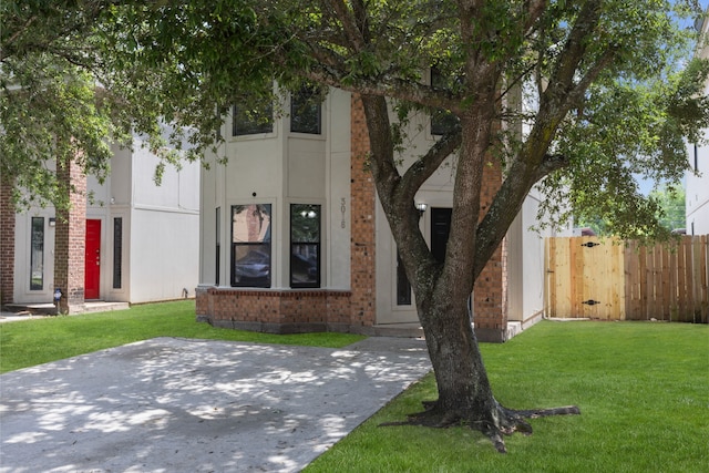 view of front of property with brick siding, fence, and a front yard