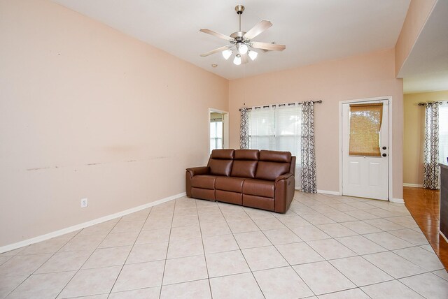 living room featuring ceiling fan, light tile patterned floors, and baseboards