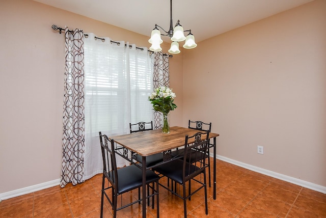 dining room with a chandelier, baseboards, and tile patterned floors