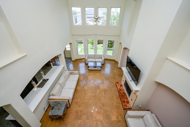living area with arched walkways, a high ceiling, ceiling fan, and a fireplace with raised hearth