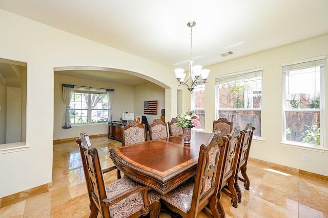 dining area with arched walkways, a notable chandelier, visible vents, and baseboards