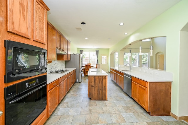 kitchen with a sink, under cabinet range hood, black appliances, and plenty of natural light