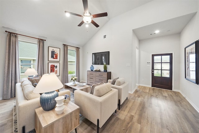 living room featuring high vaulted ceiling, visible vents, ceiling fan, light wood-style flooring, and baseboards