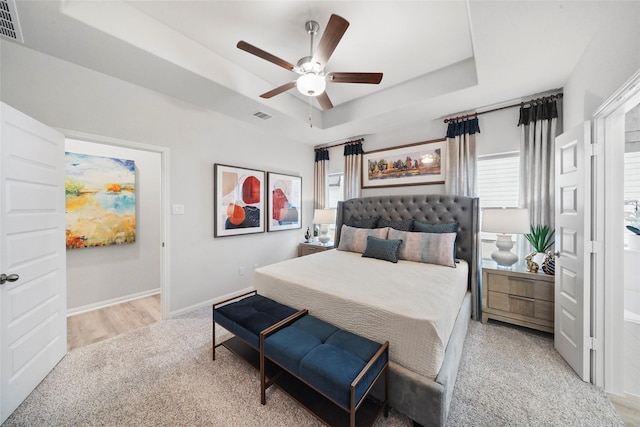 bedroom with a tray ceiling, baseboards, a ceiling fan, and visible vents